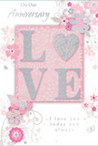 This anniversary card offers a gentle celebration of enduring romance, much like a softly coloured bouquet arriving at a Belmont doorstep on a special evening. The main focus is the word LOVE, rendered in raised, pale glitter so that it feels slightly embossed under the fingertips. The letter O is transformed into a shimmering silver heart, giving the centre of the card a focal point that glows against the surrounding blush-pink panel. Around this heart-shaped centre, delicate blossoms unfurl in blush, mauve, and powder pink, their petals painted with a watercolour softness that recalls freshly opened blooms in a carefully arranged vase. Fine, flowing lines and curling tendrils weave between the flowers, echoing the graceful stems and foliage a florist threads into an anniversary design. Subtle touches of silver highlight certain petals and swirls, adding a sense of occasion without overwhelming the card's quiet intimacy. Tiny butterflies and airy flourishes drift near the edges, suggesting movement and the lightness of shared happiness. The inscriptions On Our Anniversary and I love you today and always are written in an elegant, understated script that feels personal, as though penned by hand after a peaceful walk through Belmont's leafy streets. Every element-the pastel palette, the tactile glitter, the delicate florals-combines to create a keepsake that feels as thoughtful and heartfelt as a bespoke anniversary bouquet, ideal for marking years of shared love and new memories still to come.